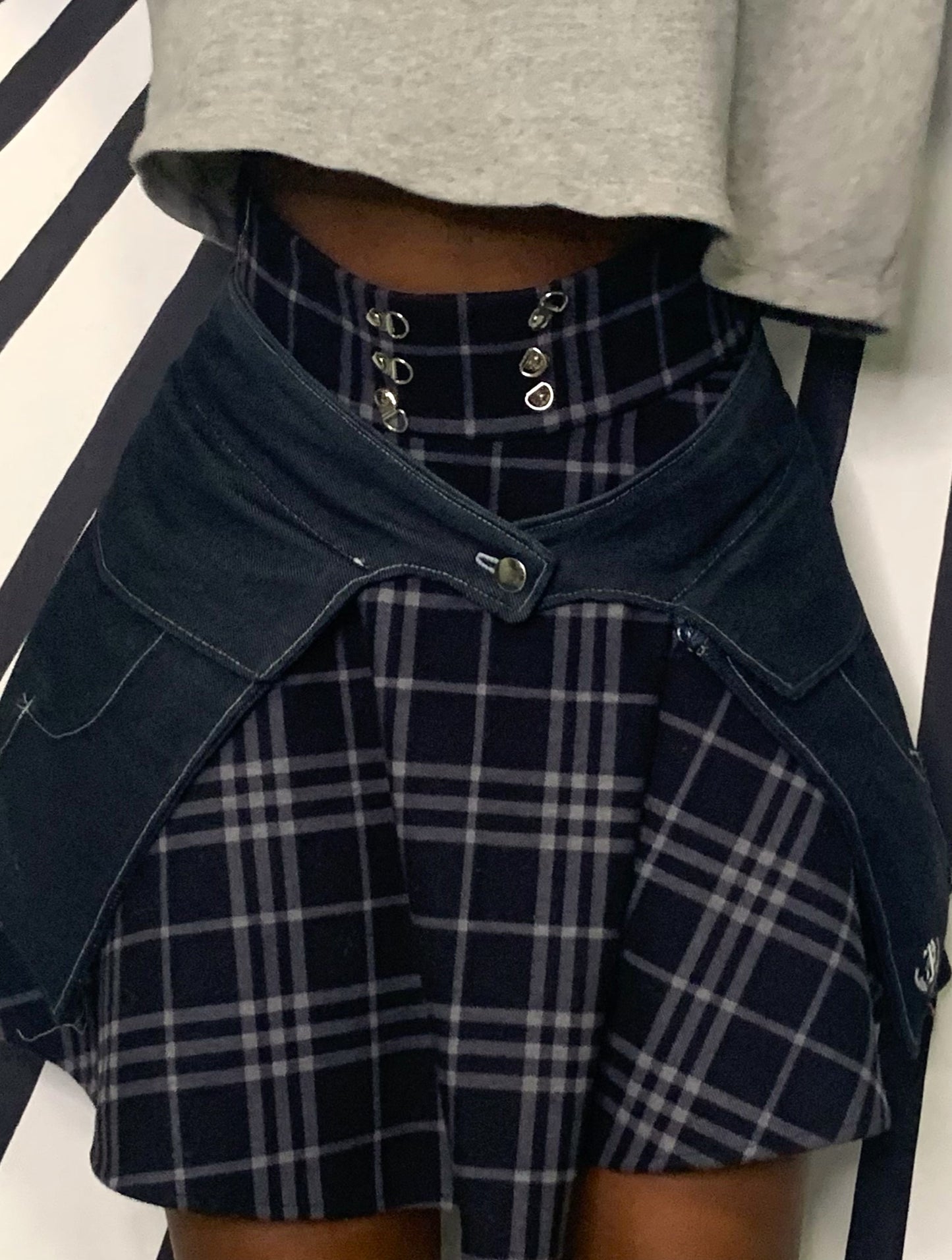 A close-up of the front view of someone wearing a pair of midnight denim pockets in front of a black and white striped background