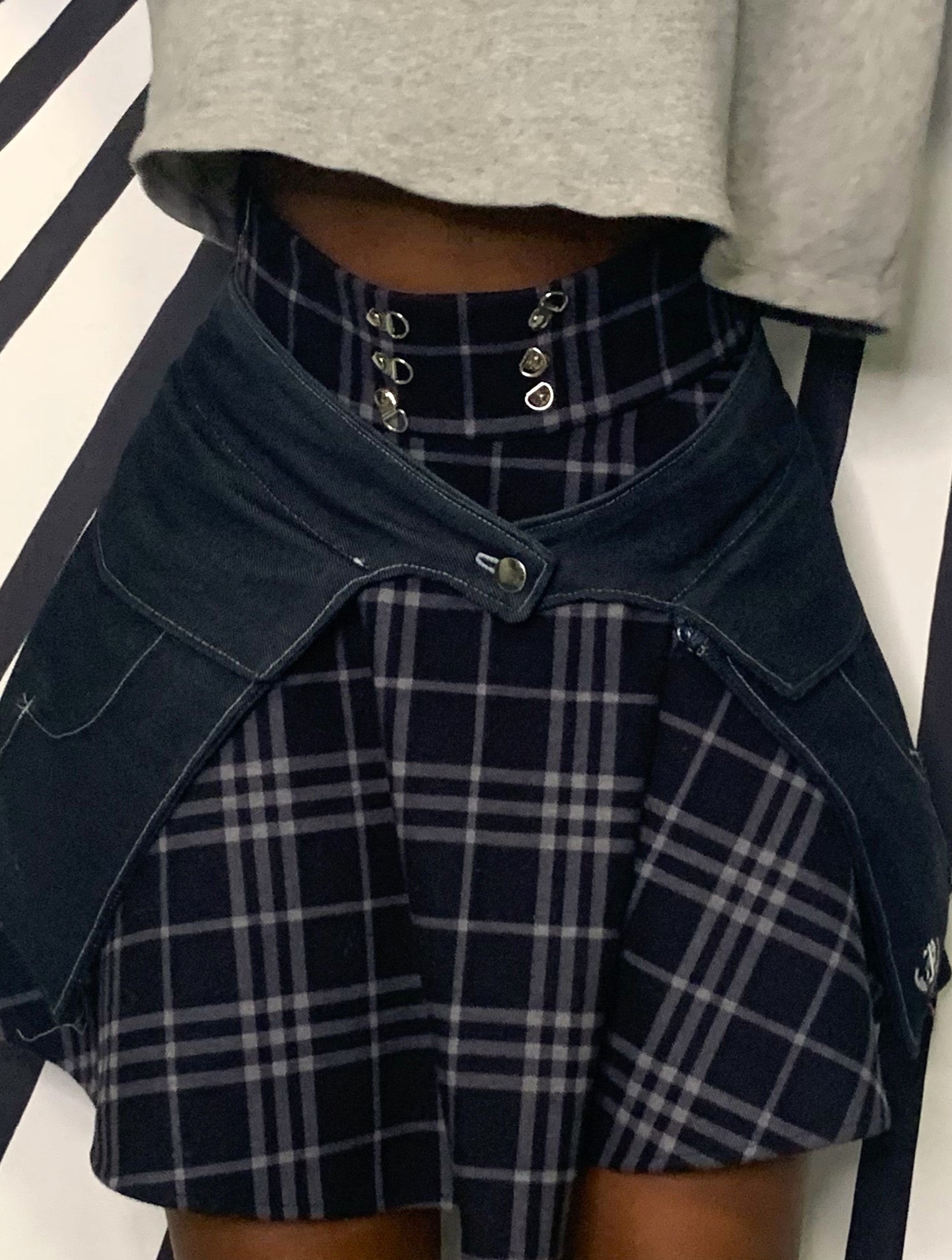 A close-up of the front view of someone wearing a pair of midnight denim pockets in front of a black and white striped background