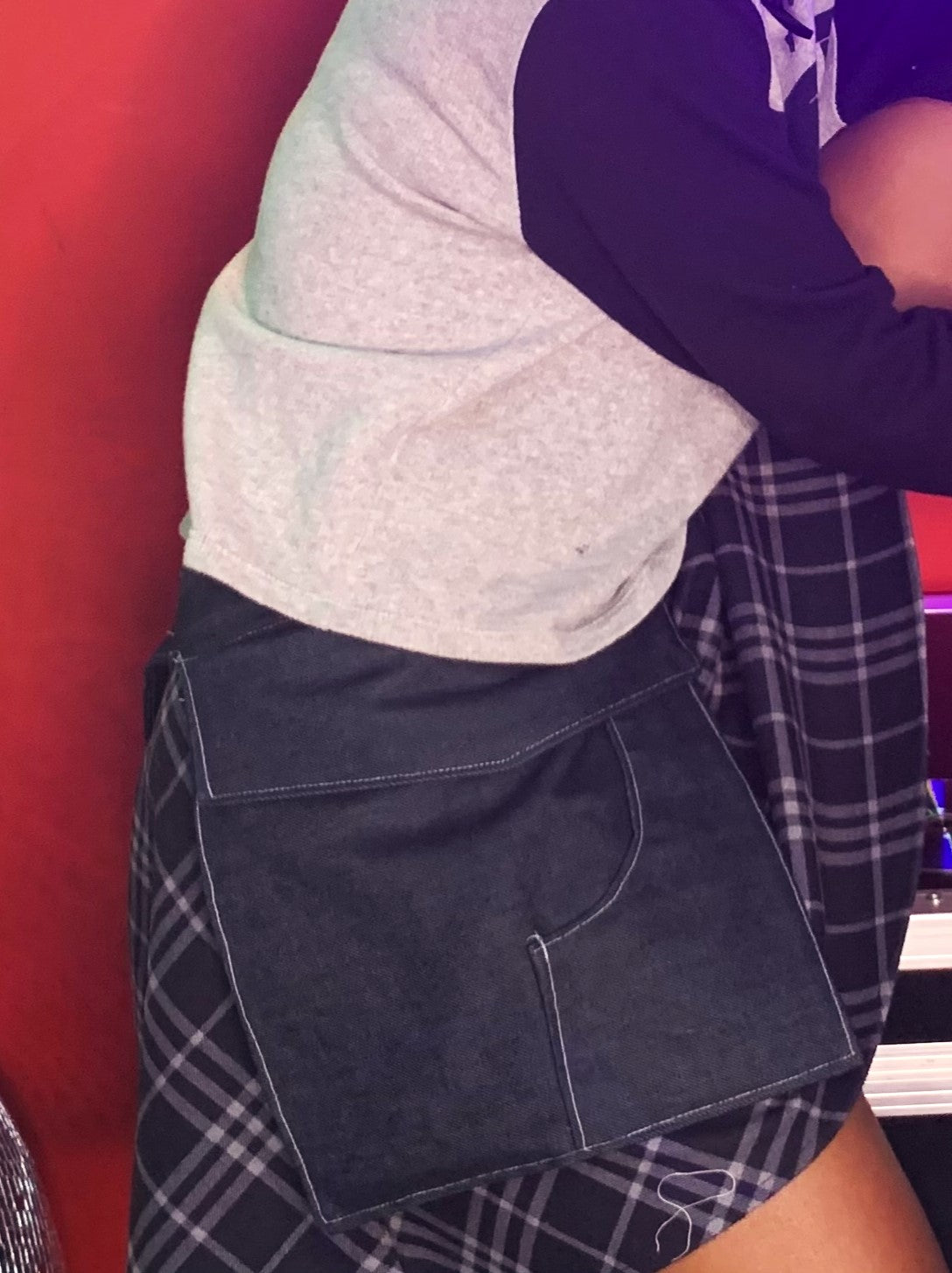a close-up side view of someoen wearing a pair of midnight denim pockets in front of a red background