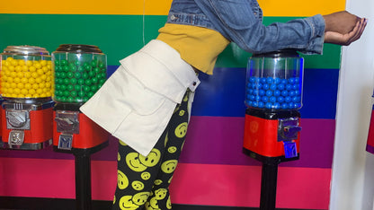 A side view of someone wearing a pair of pff-white pockets in front of a colorful background with gumball machines.